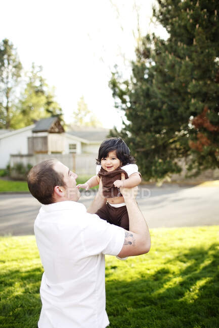 Отец держит дочь в воздухе в парке — стоковое фото