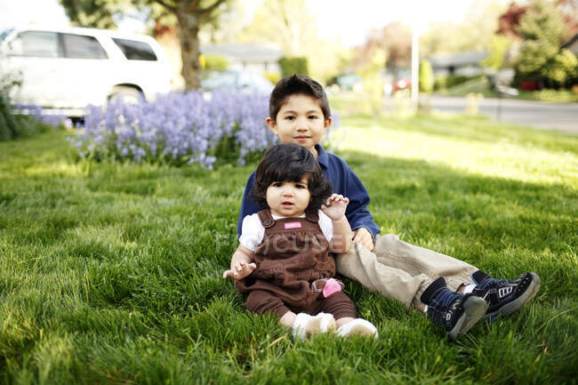 Jovem e sua irmã mais nova olhando para a câmera, no parque — Fotografia de Stock