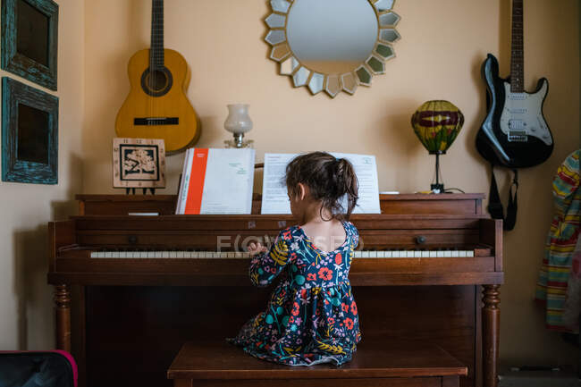 Chica tocando el piano, lindo niño preescolar practicando instrumento musical - foto de stock