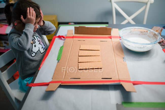 Menina casa de gengibre projeto mãos na cabeça na mesa — Fotografia de Stock