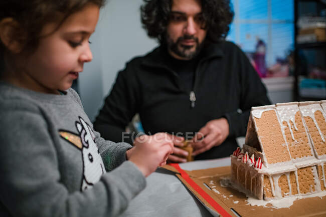 Dad and daughter building gingerbread house together — Stock Photo