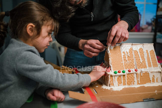Vater und Tochter bauen Lebkuchenhaus in Küche — Stockfoto
