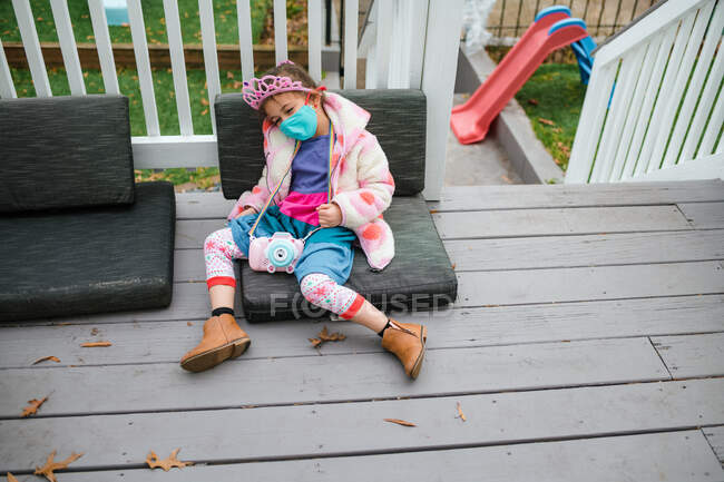 Little girl in crown slumped on deck tired from birthday party — Stock Photo