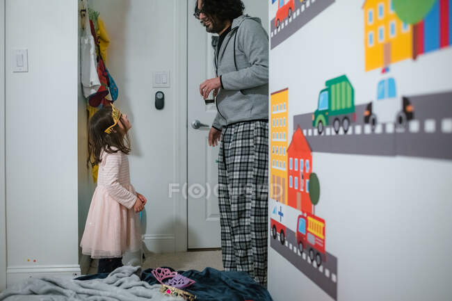 Little girl in tiara looking up at dad in domestic kids bedroom — Stock Photo