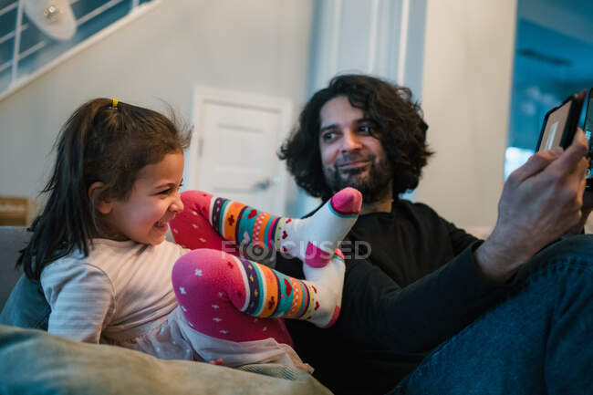 Отец и дочь вместе играют на iPad и смеются — стоковое фото