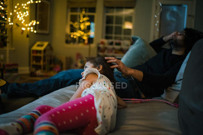 Отец и дочь отдыхают на диване и смотрят кино — стоковое фото
