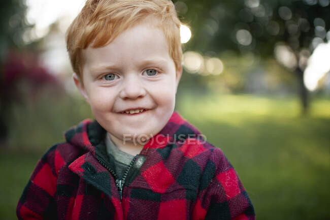 Primer plano del niño pequeño mirando y sonriendo al aire libre en abrigo de invierno - foto de stock