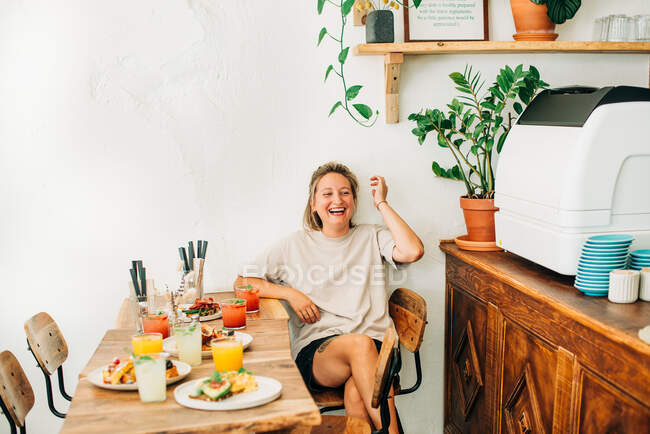 Young woman laughing while sitting in cafe — Stock Photo