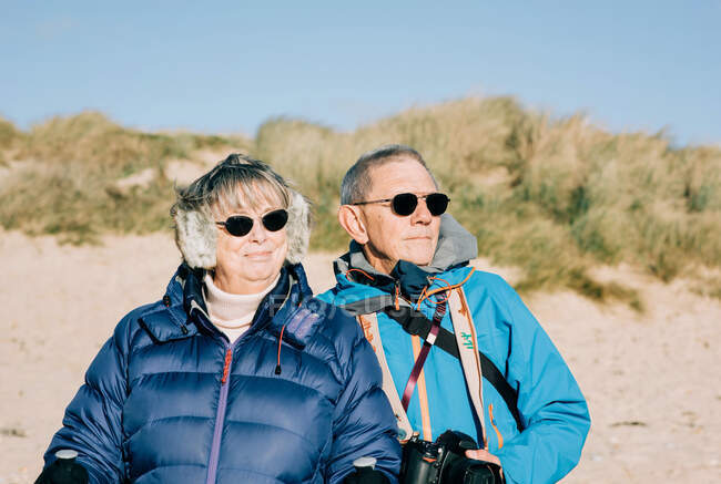 Пара в свои 70 стояли на пляже, глядя на море — стоковое фото