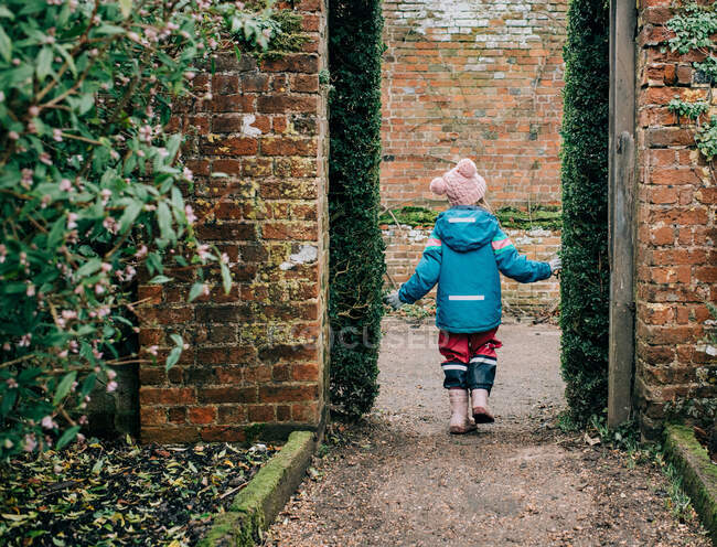Child walking through an English country garden in winter — Stock Photo