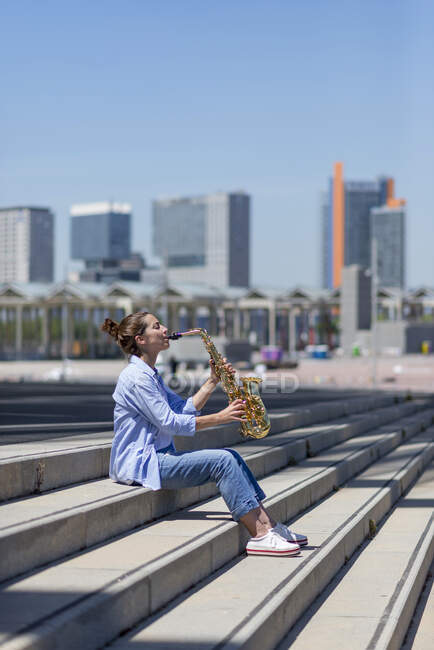 Frau mit Pferdeschwanz spielt Saxofon im Freien — Stockfoto