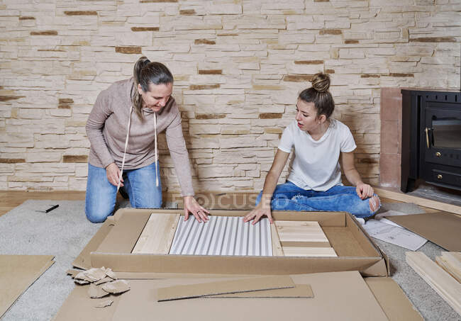 Front view of two women getting a piece of wood or shelf from a — Stock Photo