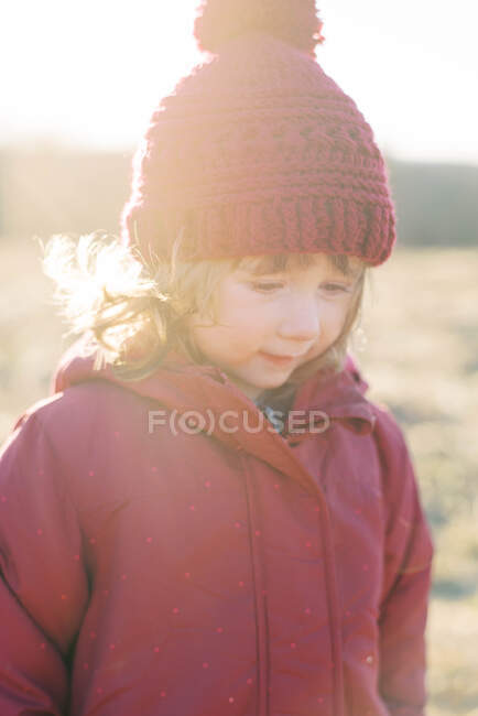 Petite fille portant des vêtements d'hiver et chapeau au crochet pendant le coucher de soleil froid — Photo de stock