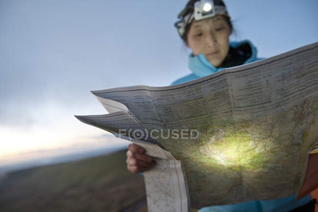 Senderista mujer leyendo mapa de senderismo en Pen Y Fan en Gales al amanecer - foto de stock