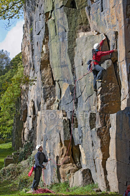 Woman climbing up steep rock face in the UK — Stock Photo