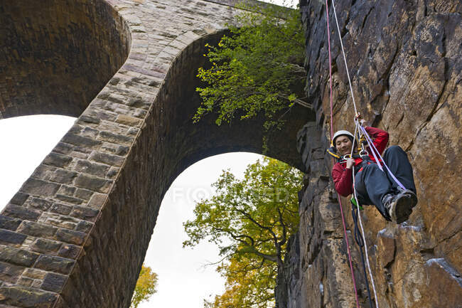 Woman practising high rope access technique under viaduct in the UK — Stock Photo