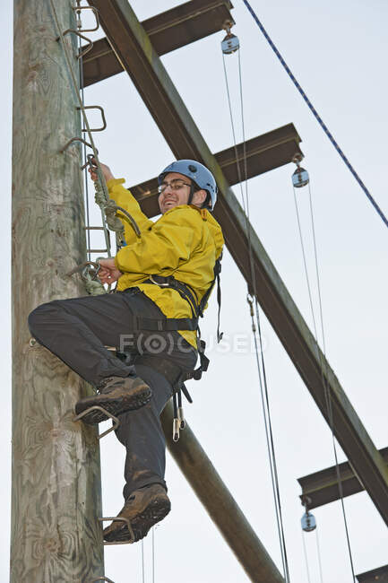 Man ascending wooden pole at high rope training exercise — Stock Photo
