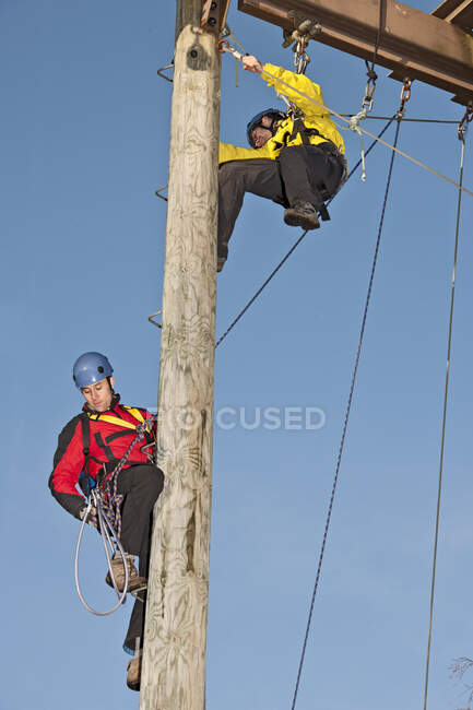 Deux hommes travaillant sur un poteau en bois lors d'un exercice d'entraînement à la corde — Photo de stock