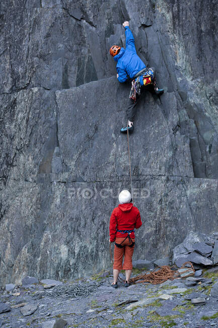 Uomo che si arrampica sulla ripida parete rocciosa della cava di ardesia nel Galles del Nord — Foto stock