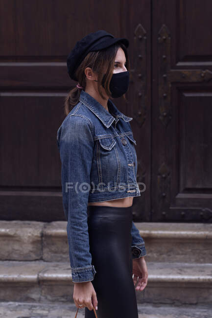 Jeune femme avec masque marche à travers la ville — Photo de stock