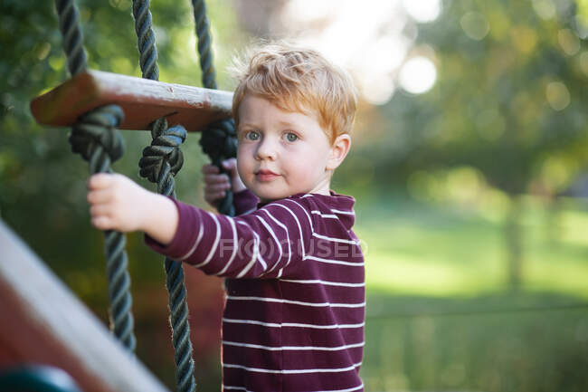 Close up of boy 3-4 years old climbing ladder on playlet in backyard — Stock Photo