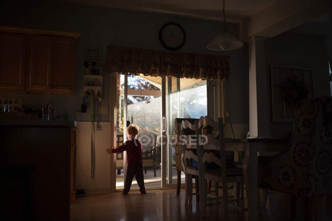 Menino 3-4 anos de idade porta de abertura na cozinha em luz bonita e sombras — Fotografia de Stock