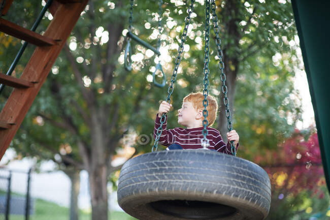Glücklicher kleiner Junge im Alter von 3-4 Jahren schaukelt auf einer Reifenschaukel im Hinterhof — Stockfoto