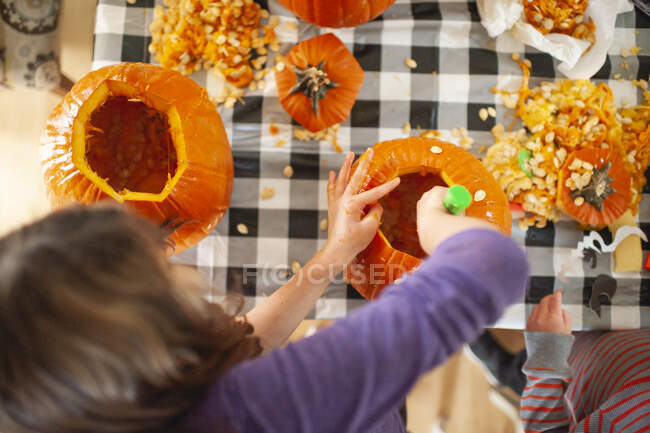Au-dessus de la tête des enfants ramassant des graines de citrouille à table — Photo de stock
