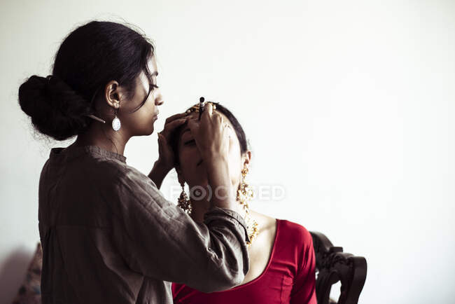 Young Indian woman applies make up to bride before Indian wedding — Stock Photo