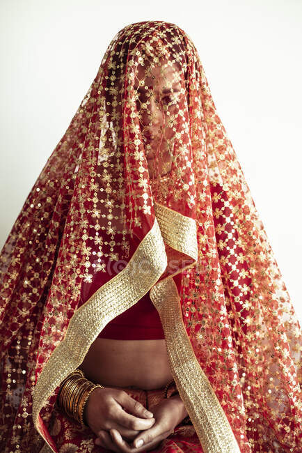 Індійська наречена перед весіллям дивиться з - під традиційної червоної завіси. — стокове фото