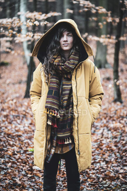 Forte giovane donna sta con giacca incappucciata in autunno foglie forrest — Foto stock