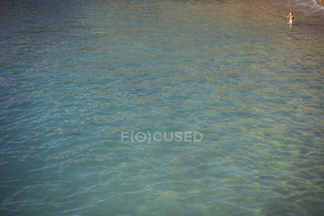 Schöner blauer Ozean mit einer einzigen Frau, die in einer Ecke des Rahmens badet — Stockfoto