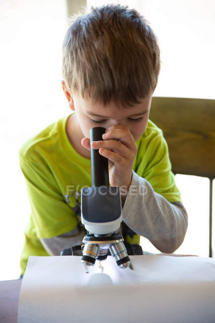 Close up de menino olhando através de um microscópio para um bug — Fotografia de Stock
