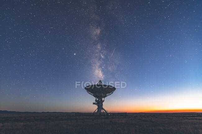 Telescopio satélite sobre campo de trípode y fondo nocturno estrellado - foto de stock