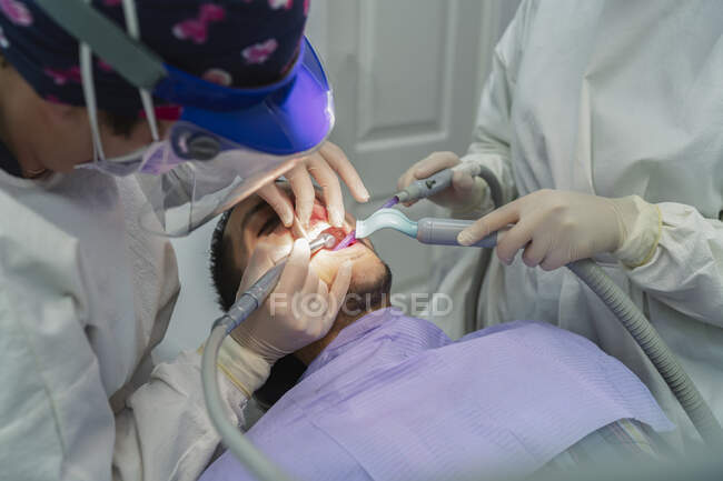 Équipe de dentistes retirant une dent d'un patient — Photo de stock