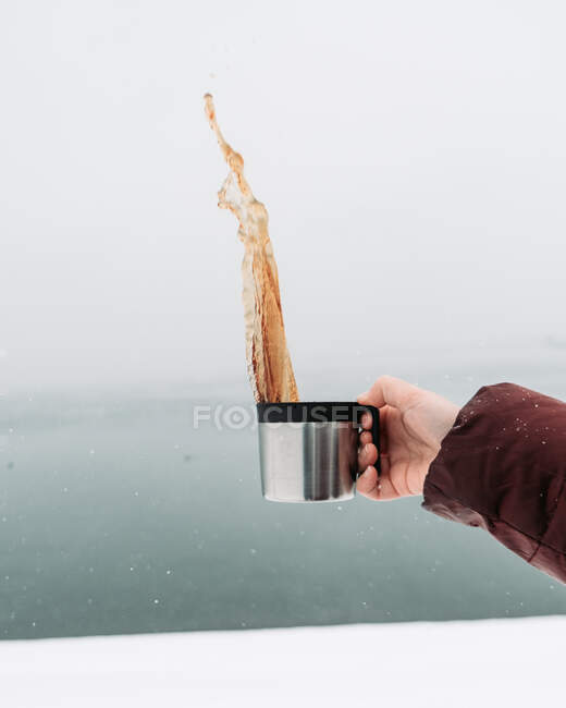 Hand gießt einen Metallteller und einen weißen Hintergrund — Stockfoto