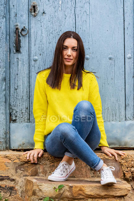Retrato de una joven sentada en los escalones de una vieja casa. Concepto de viajes y turismo. - foto de stock