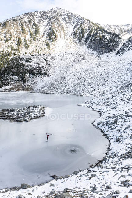 Drone view of hockey player skating on frozen lake near mountains — Stock Photo