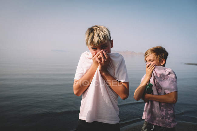 Niños cubren sus narices para evitar el olor a azufre en Great Salt Lake. - foto de stock