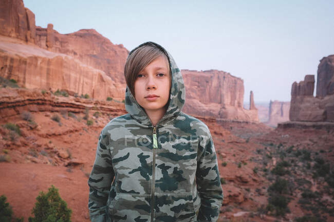 Boy in Camo en Park Avenue View Point en el Parque Nacional Arches en Dawn - foto de stock