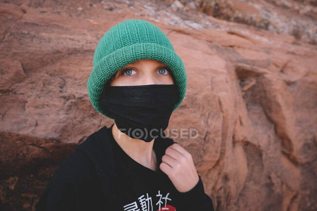 Garçon avec de grands yeux bleus jette un coup d'oeil derrière un masque. — Photo de stock