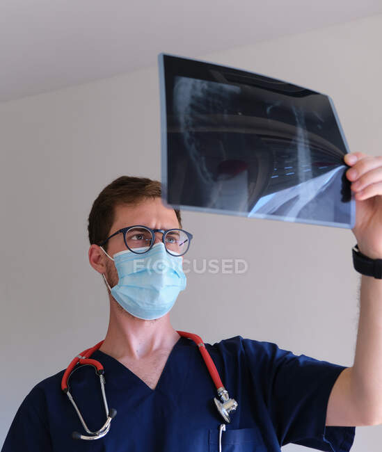 Un médico guapo mirando a una radiografía - foto de stock