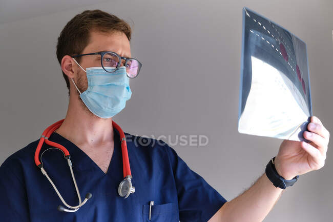 Un médico guapo mirando a una radiografía - foto de stock