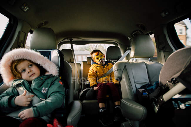Niño y niña sentados en el coche - foto de stock