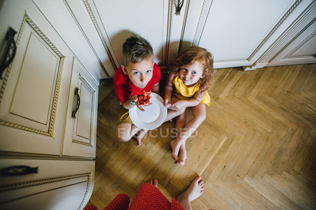 Niño y niña comiendo pastel de fresa - foto de stock