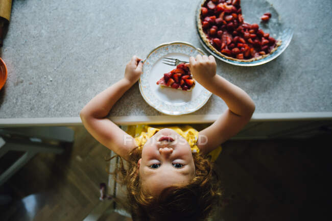 Девушка ест клубничный десерт и улыбается — стоковое фото