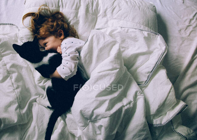 Дівчинка грає з котом у ліжку. — стокове фото