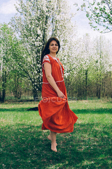 Donna in abito rosso che danza tra gli alberi — Foto stock