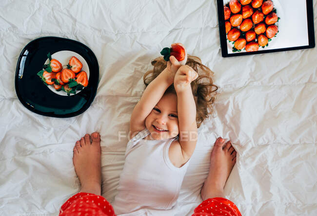 Girl holding strawberry and laughing — Stock Photo