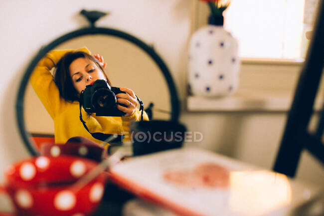 Mujer mirando al espejo y sosteniendo la cámara - foto de stock